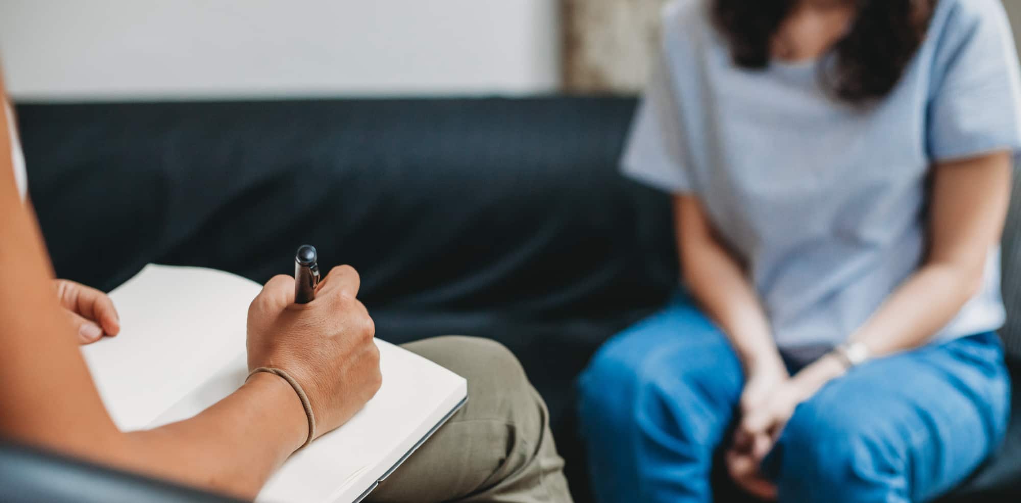 Woman sits with her psychologist addressing behaviors understanding her addiction as clinical diagnosis.