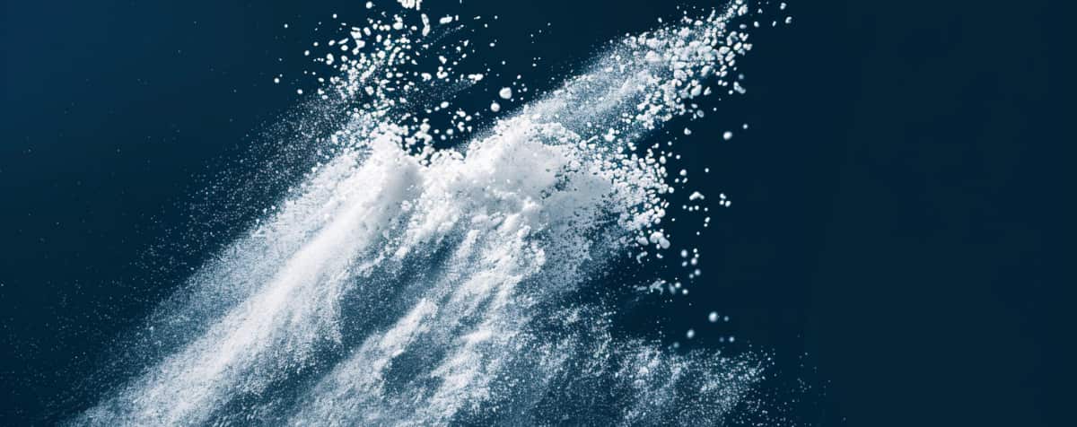 White powder across a blue background showing that cocaine is often laced with other substances.