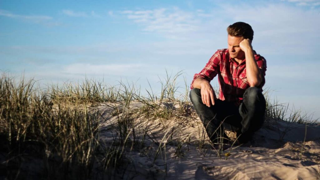 Man sits on the beach in the South Bay area contemplating if white kratom is safe. 